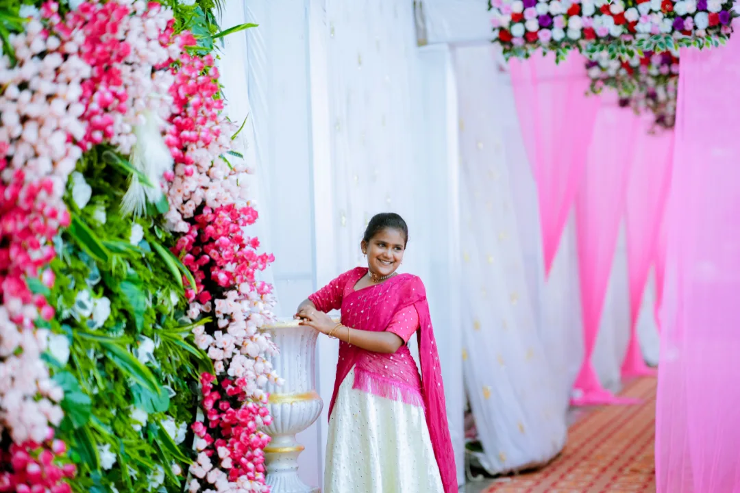girl posing beside elegant floral backdrop with pink drapes