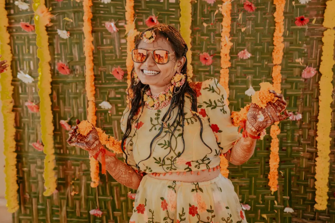 Bride enjoying haldi ceremony with flower shower during wedding rituals - best wedding decoration in bangalore