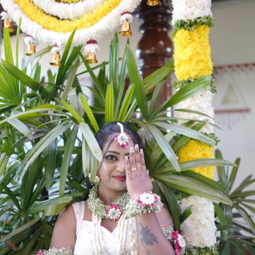Bride in traditional attire posing against floral and green wedding backdrop - best wedding decoration in bangalore