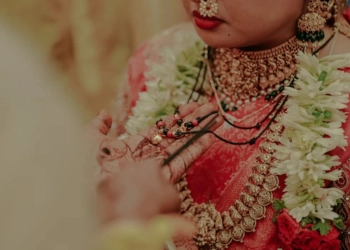 Close-up of bride in red saree wearing green bangles and gold jewelry
