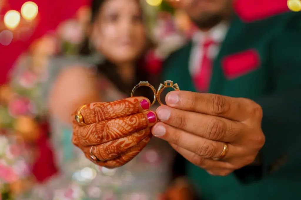 Close-up of bride and groom holding wedding rings at a Bangalore engagement ceremony