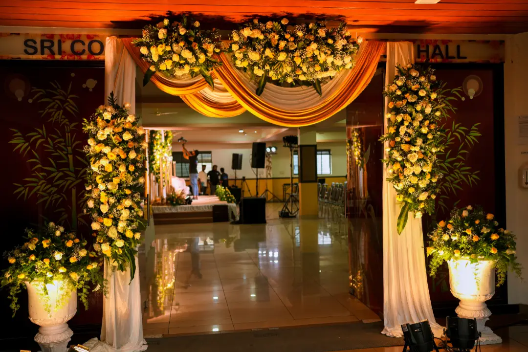 Grand wedding entrance decorated with orange and yellow floral drapes.