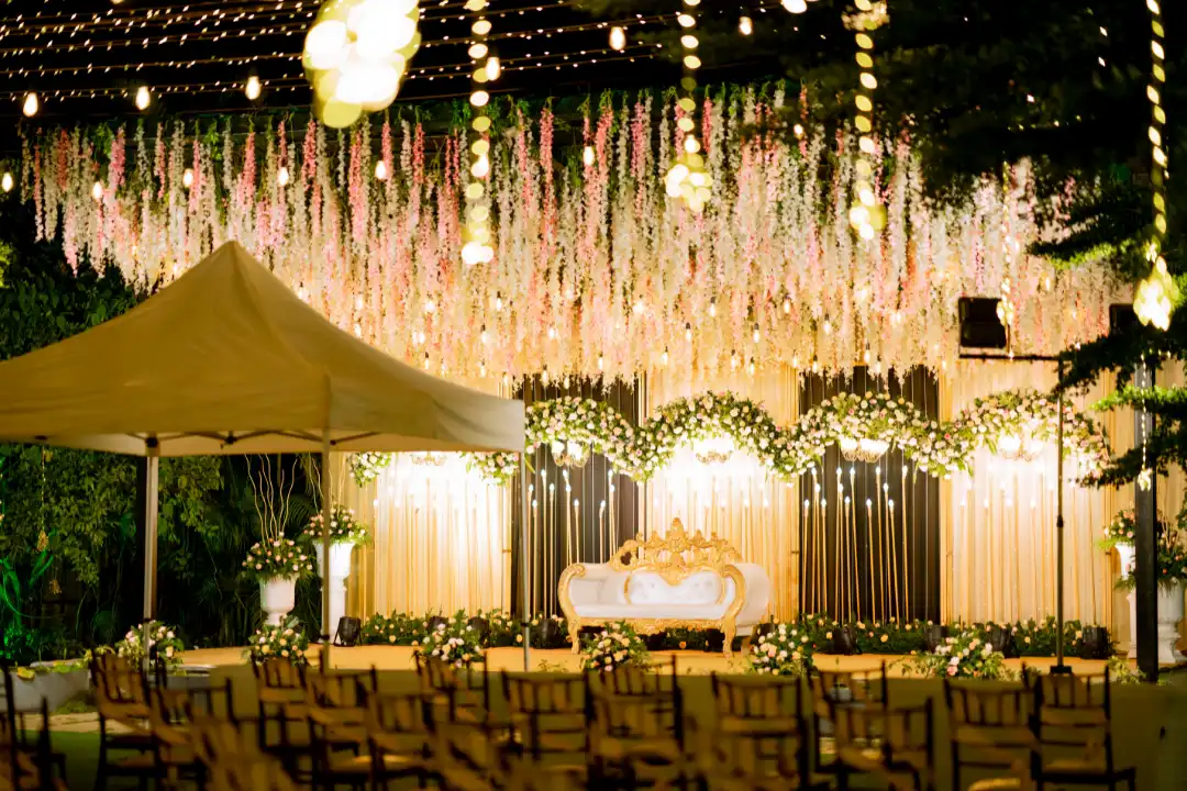 Luxurious wedding reception hall with golden chandeliers and floral ceiling decor.