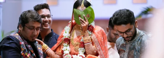 Bride covering her face with betel leaves during Bengali wedding ritual in Bangalore.
